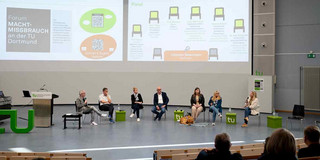Alle sieben Teilnehmer*innen und der Moderator der Podiumsdiskussion beim Forum Machtmissbrauch an der TU (23. Oktober 2024), fotografiert aus einier Entfernung und aus der Publikumsperspektive.